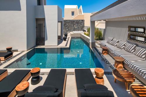 an indoor swimming pool with lounge chairs and a swimming pool at Uma Ray Suites in Fira