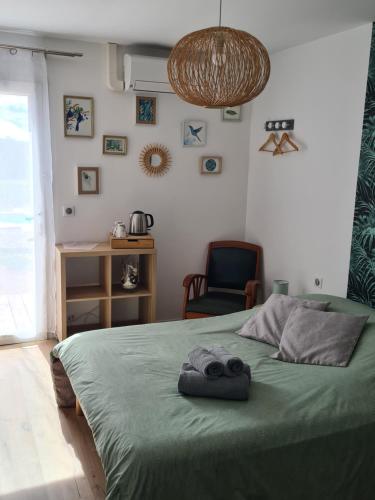 a bedroom with a green bed with a chair at Le Petit Chêne in Orgnac-lʼAven