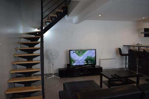 a living room with a spiral staircase and a television at Maison mitoyenne tout confort et parking securise. in Juillan