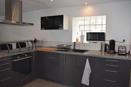 a kitchen with a counter with a sink and a microwave at Maison mitoyenne tout confort et parking securise. in Juillan