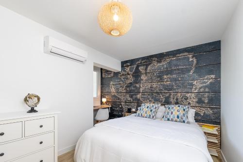 ein Schlafzimmer mit einem weißen Bett und einer Holzwand in der Unterkunft Superbe T2 Juan Les Pins 300m des plages in Antibes