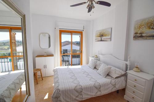 um quarto branco com uma cama e um espelho em Casa Clara, Frigiliana 2 Bedroom Apartment with communal pool HansOnHoliday Rentals em Frigiliana