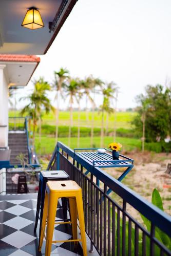 a table and two yellow stools on a porch at Lavini Hoian Boutique Villa in Hoi An