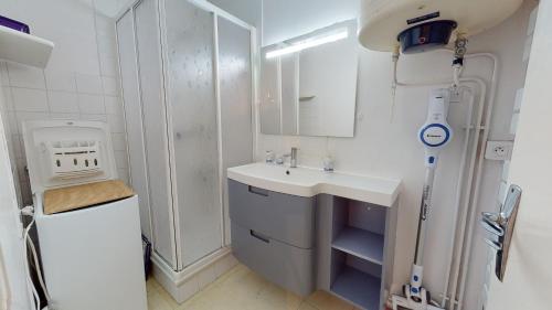 une salle de bain blanche avec un lavabo et une douche dans l'établissement Le Dauphin Bleu face mer, à Plage-des-Demoiselles