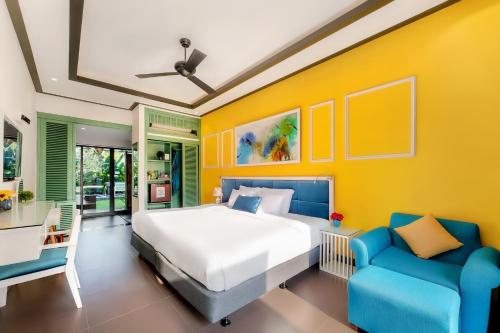 a bedroom with a bed and two blue chairs at Lavini Hoian Boutique Villa in Hoi An