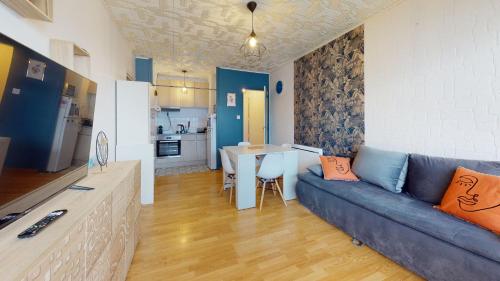 un salon avec un canapé bleu et une cuisine dans l'établissement Le Dauphin Bleu face mer, à Plage-des-Demoiselles