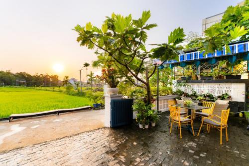 d'une terrasse avec une table, des chaises et un arbre. dans l'établissement Lavini Hoian Boutique Villa, à Hội An