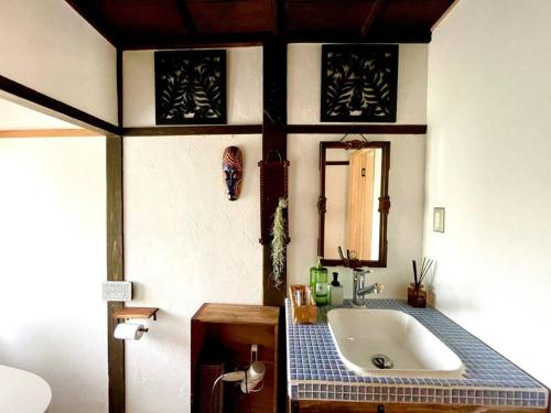 uma casa de banho com uma banheira e um lavatório em 一棟貸し切り バリの雰囲気を楽しめる古民家vintagehouse1925Bali em Nagano