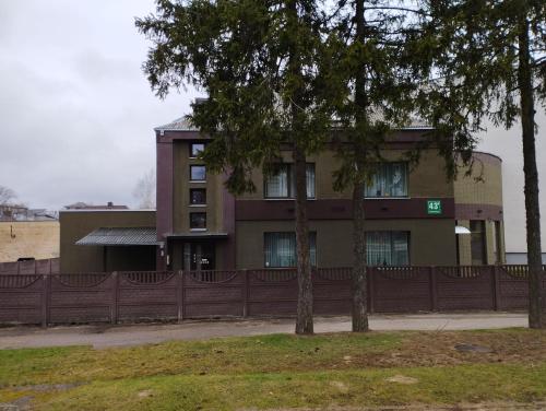 a building with a fence and two trees in front at Vila 1936 in Šiauliai