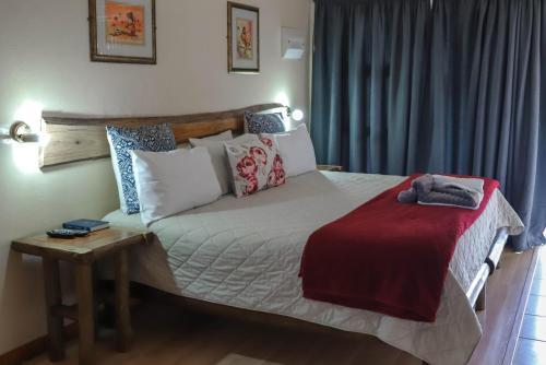 a bedroom with a large bed with a red blanket at Lodge Laske Nakke in Lydenburg