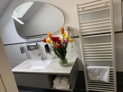 a bathroom with a sink and a mirror and flowers at Garni San Paolo in Appiano sulla Strada del Vino