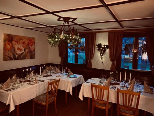 une salle à manger avec des tables et des chaises blanches et un lustre dans l'établissement Landgasthof Anker, à Simmersfeld