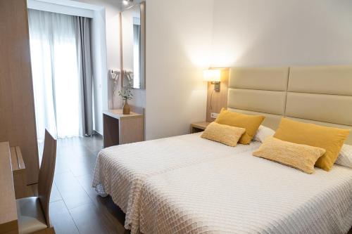 a bedroom with a large bed with yellow pillows at Hostal La Cigüeña in Portinatx