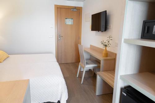 a small room with a bed and a desk at Hostal La Cigüeña in Portinatx