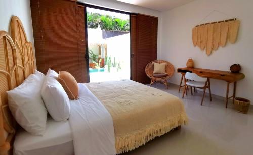 een slaapkamer met een bed, een bureau en een raam bij Villa Anoli - 3 chambres - Centre de Seminyak in Seminyak