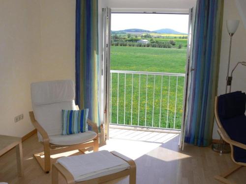 a living room with a chair and a door to a balcony at Komfort Ferienwohnung II Wolfhagen in Wolfhagen
