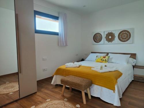 1 dormitorio con 1 cama con manta amarilla y silla en Villa Jardín Atteneri, en La Vegueta