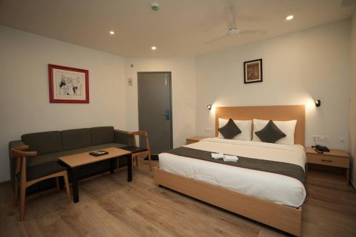 a bedroom with a bed and a couch and a table at GRAND GANPAT in Vellore