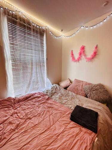 Studio flat in Stratford في لندن: غرفة نوم مع سرير وملاءات وردية ونافذة