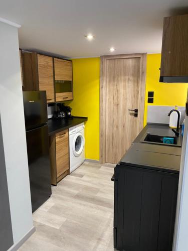 - une cuisine avec des murs jaunes et un réfrigérateur noir dans l'établissement Kyma Holiday Loft, à Artemi
