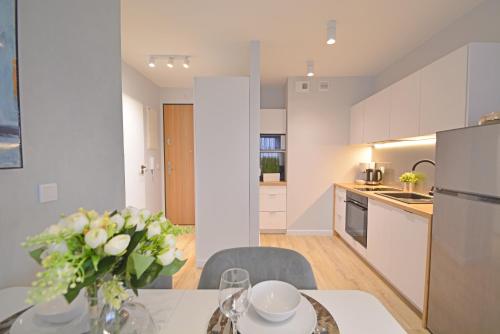 a kitchen and dining room with a table with a vase of flowers at Sun Towers - Apartamenty Bryza - Apartamenty z parkingiem in Świnoujście