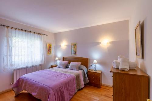 Un dormitorio con una cama con sábanas moradas y una ventana en CASA NIDES, en Doade