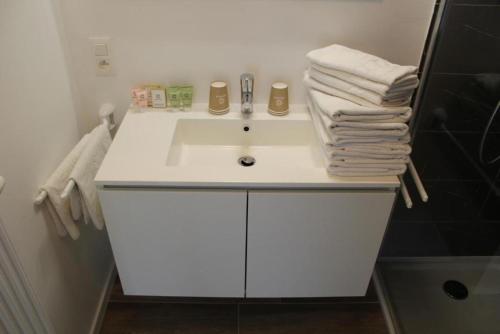 a bathroom with a white sink and towels at West Bay Familieappartement in Middelkerke