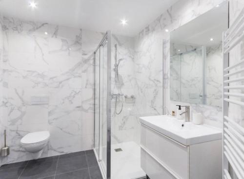 a white bathroom with a toilet and a sink at Deux logements voisins au calme Olivia et Victoria in Saint-Pair