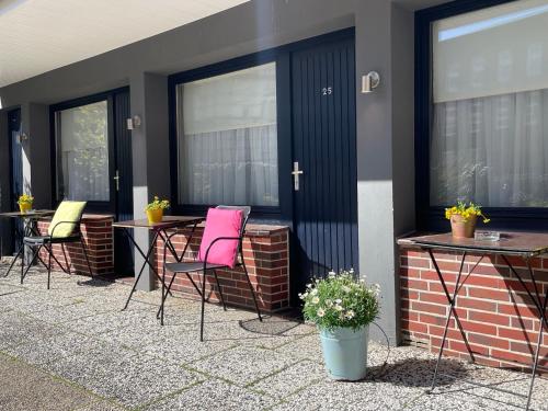 a patio with pink chairs and tables and windows at City Hostel by beans parc in Wilhelmshaven