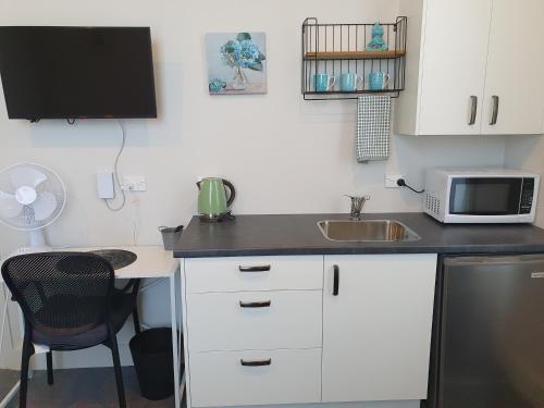 a small kitchen with a sink and a microwave at Work Stay at 123 in Dunedin