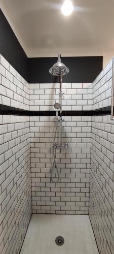 een badkamer met een douche en witte betegelde muren bij Gîte de l'Abeille 