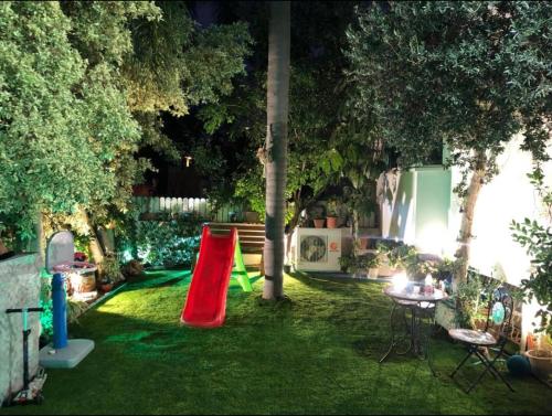 a backyard with a red slide in the grass at Beautiful design Studio in Rishon LeẔiyyon