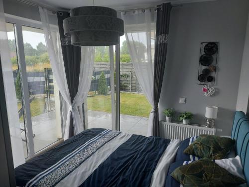 a bedroom with a bed and a large window at Apartament Sarbinowo in Sarbinowo