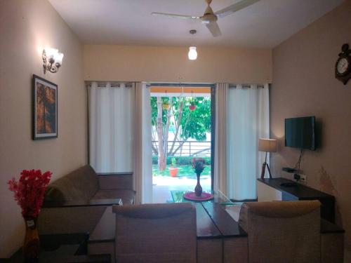 a living room with a couch and a table and a window at Portofino TreeHouse in Lavasa