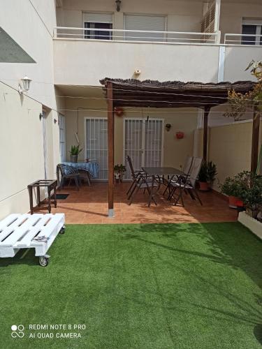 un patio con una mesa y sillas en el césped en El Rincón de Triana, en Almería
