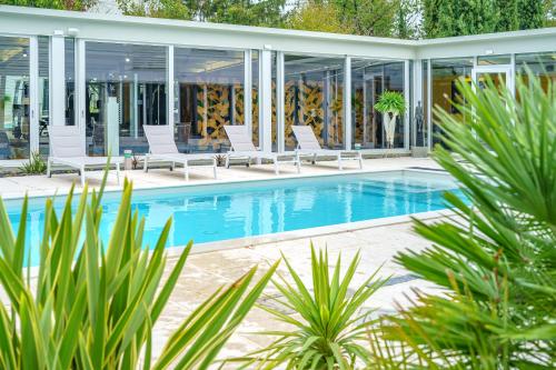 uma piscina com cadeiras brancas e uma casa em VILLA VITTORIA B&B - Wellness em Terme di Miradolo