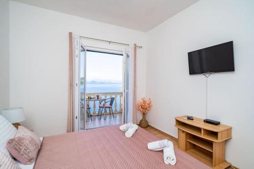 a bedroom with a bed and a television and a balcony at By the sea in Sobra
