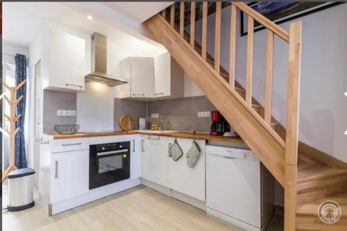 une cuisine avec des placards blancs et un escalier dans l'établissement Gîte « Les Embruns », à Cosqueville