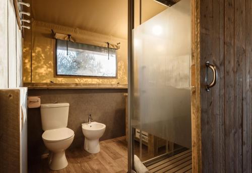 uma casa de banho com um WC e uma cabina de duche em vidro. em Glamping Tenuta Poggio Rosso em Populonia