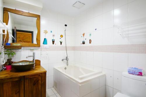 uma casa de banho branca com um lavatório e uma banheira em Yilan B&B - Happy Snail em Wujie