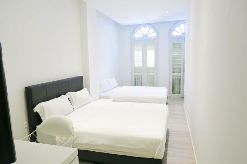 two beds in a room with white walls and a window at Comfy Studio 6 by ReCharge in Singapore