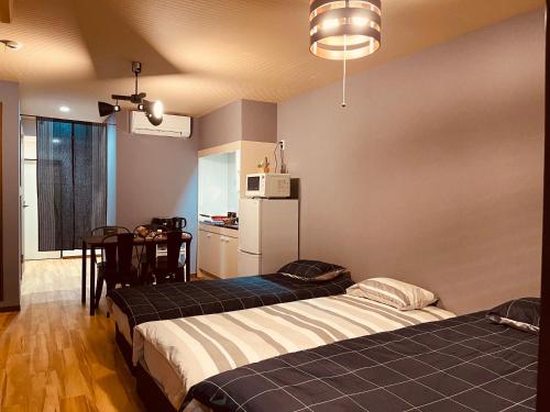 a room with two beds and a kitchen with a table at Namba Shinsaibashi 10 mins Reiko guest house in Osaka