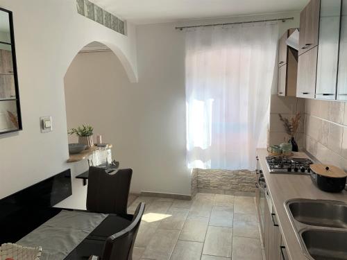una cucina con lavandino, tavolo e finestra di Apartment Lupo a Vodnjan (Dignano)