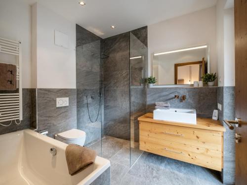 a bathroom with a tub and a sink and a shower at Ferienwohnung Hammerwirt in Fieberbrunn