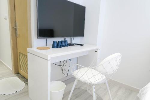 Elle comprend un bureau blanc avec une télévision et 2 chaises. dans l'établissement Comfy Studio 5 by ReCharge, à Singapour