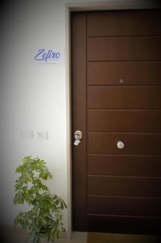 a wooden door with a plant next to it at Zefiro Holiday Home in Agropoli