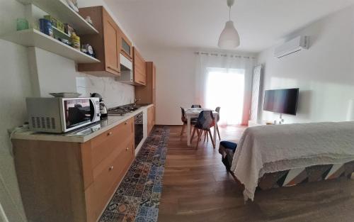 a bedroom with a bed and a kitchen with a microwave at Zefiro Holiday Home in Agropoli