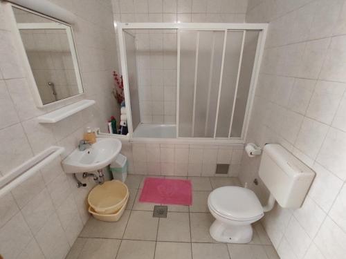 a white bathroom with a toilet and a sink at Keran 4 in Podgora