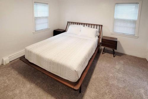 a bed with a wooden frame in a room with two windows at Waterfront Cottage near Lambeau and Door County! in Green Bay