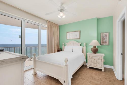 um quarto com uma cama branca e uma varanda em Emerald Isle 1201 em Panama City Beach